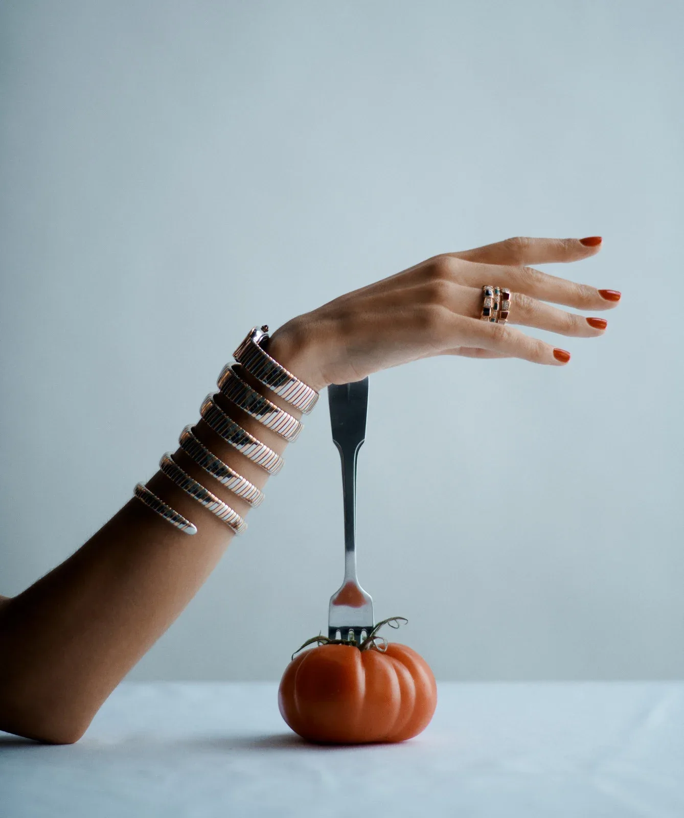 Editorial still life — hand, fork and tomato